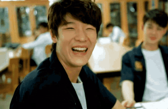 a man is laughing while sitting at a table with other people