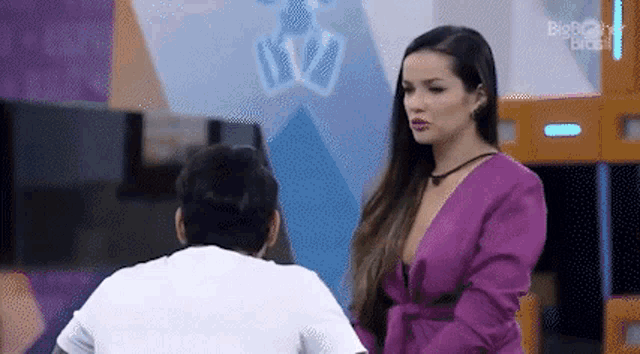 a woman in a purple dress is standing next to a man in a white shirt in a room .