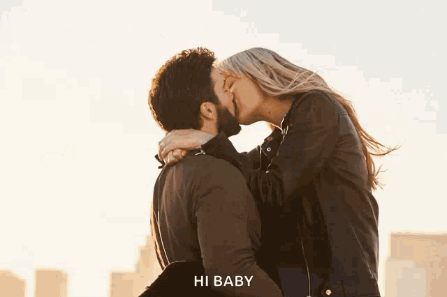 a man is carrying a woman in his arms and kissing her in front of a city skyline