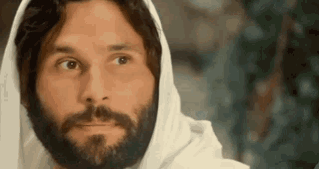 a close up of a man with a beard wearing a white robe and hood .