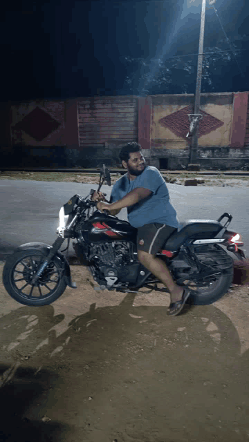a man sits on a black motorcycle with a red emblem on the front