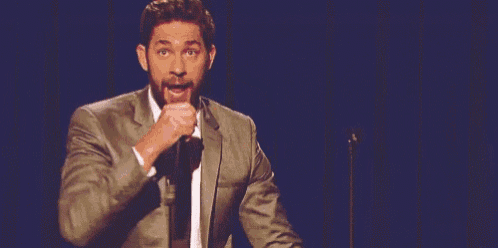 a man in a suit and tie is singing into a microphone with his arms outstretched