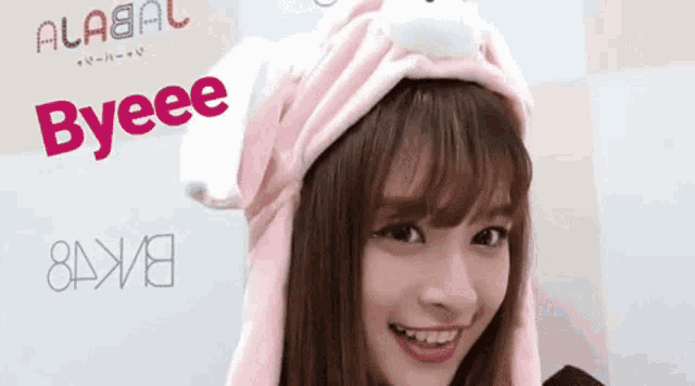 a girl wearing a pink bunny hat with the word byeee written on it