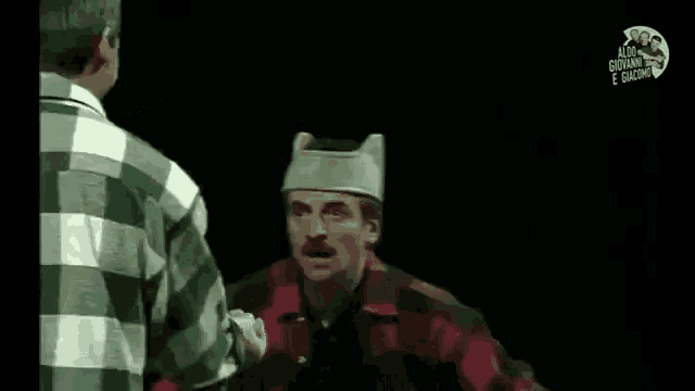 two men are standing next to each other on a stage and one of them is wearing a crown on his head .