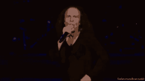 a man singing into a microphone in a dark room