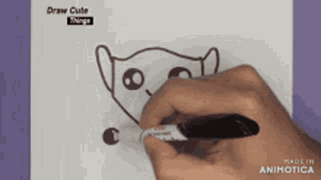 a person is drawing a cat with a marker on a piece of paper ..