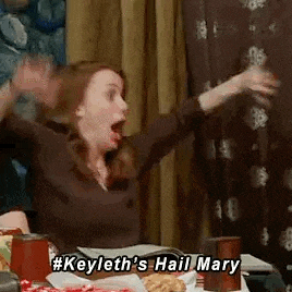 a woman is sitting at a table with her hands in the air .