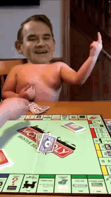 a naked man is sitting at a table with monopoly cards