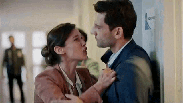 a man and a woman are standing next to each other in a hallway and kissing .