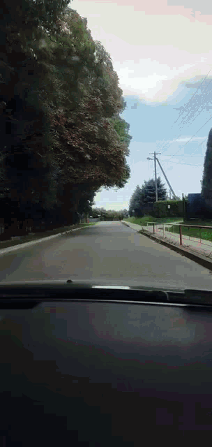 a car driving down a street with trees on both sides