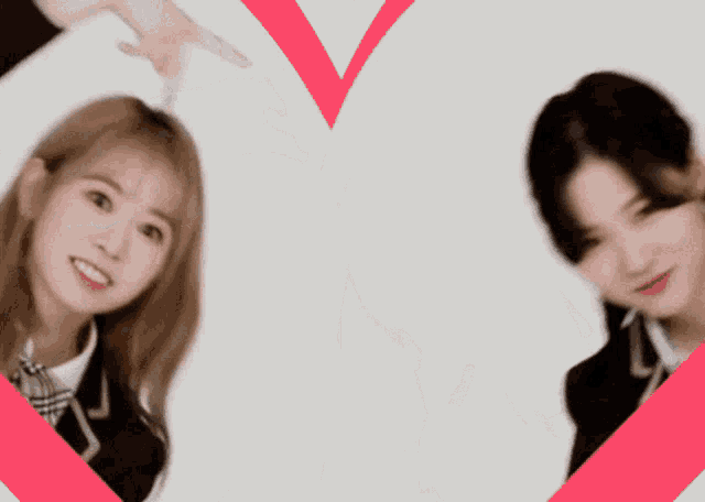 two girls in school uniforms are making a heart shape with their hands