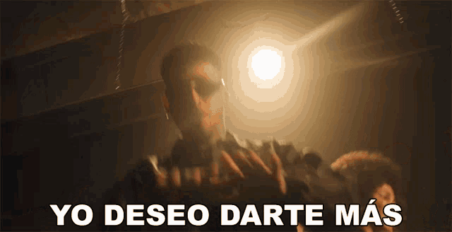 a man in a dark room with the words yo deseo darte mas written below him