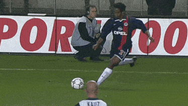 a soccer player wearing an opel jersey is kicking the ball