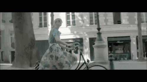 a woman in a floral dress is riding a bike down a city street .