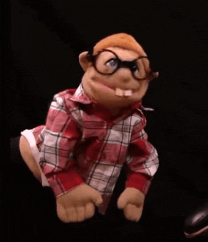 a man is holding a puppet with glasses and a plaid shirt on .