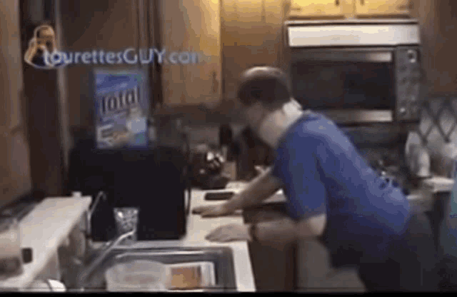 a man is standing in a kitchen with a bag of total on the counter