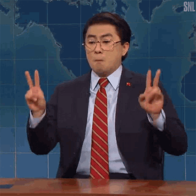 a man in a suit and tie is giving a peace sign .