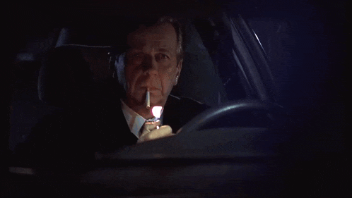 a man is smoking a cigarette while driving a car