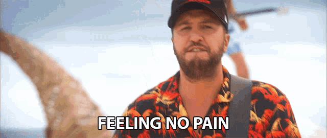 a man with a beard wearing a hawaiian shirt says feeling no pain