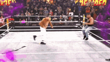 two men are wrestling in a ring with a crowd in the background