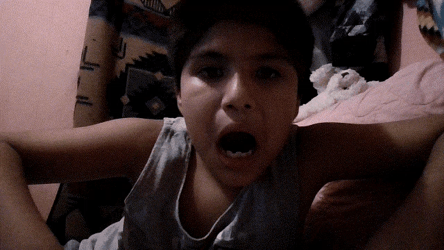 a young boy with his mouth open and a blanket behind him