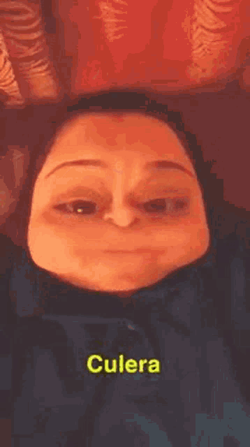 a woman is making a funny face while laying on a couch with a caption that says culera .