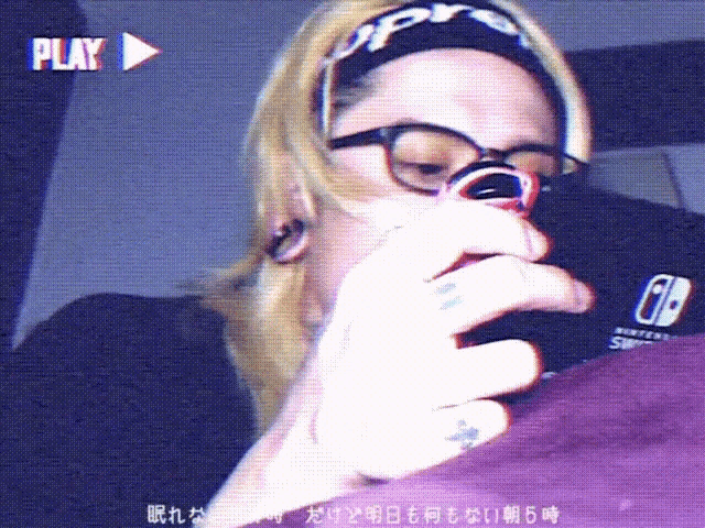 a person wearing glasses and a headband that says supreme is holding a nintendo switch