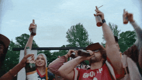 a man wearing a shirt that says gp on it is drinking from a bottle