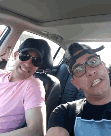 two men in a car one wearing a pink shirt