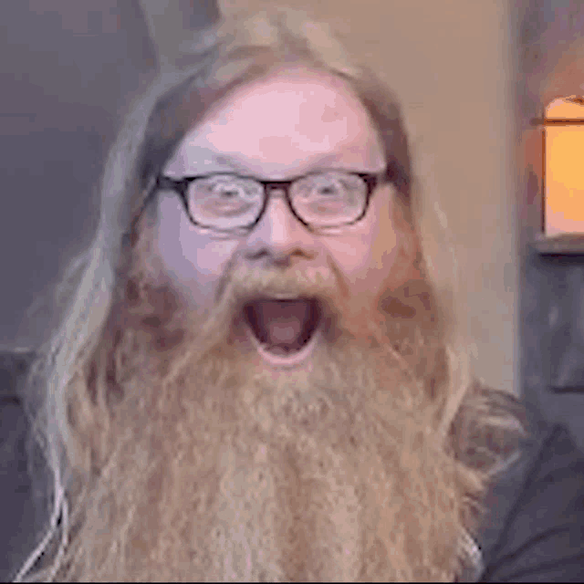 a man with glasses and a beard is making a surprised face .