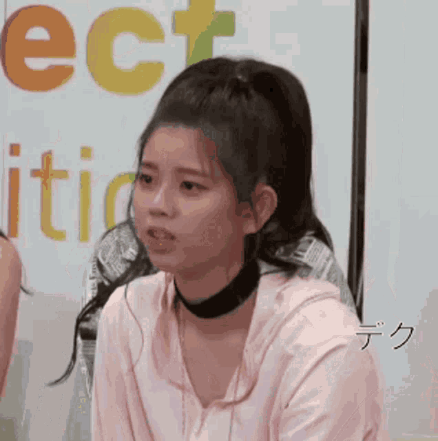 a girl wearing a choker and a ponytail is sitting in front of a sign that says ' ect '