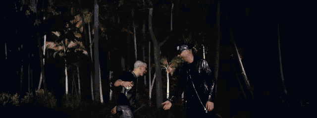 two men are shaking hands in the woods with flames coming out of their hands