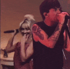 a man singing into a microphone with a tattoo on his arm