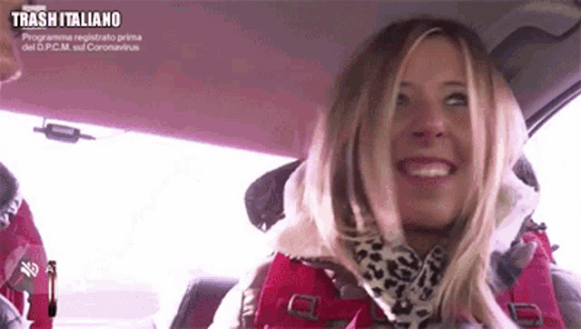 a woman is sitting in the driver 's seat of a car smiling .