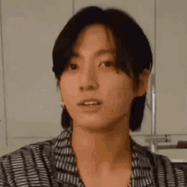 a close up of a person 's face with long hair and a striped shirt .