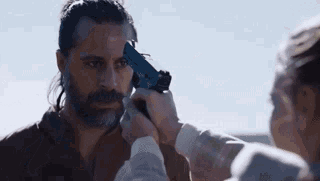 a man with a beard is being shot in the head by a woman .