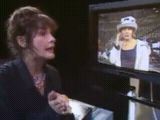 a woman is standing in front of a tv screen with a picture of a man on it