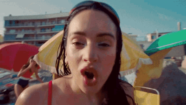 a woman in a bikini is standing on a beach with umbrellas