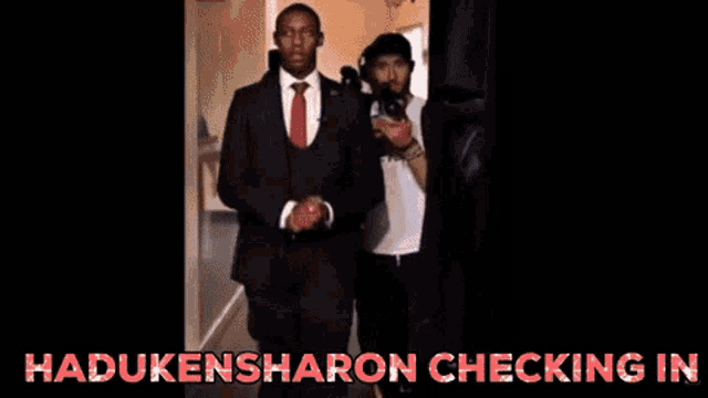 a man in a suit stands in a stadium with the words hadukensharon checking in