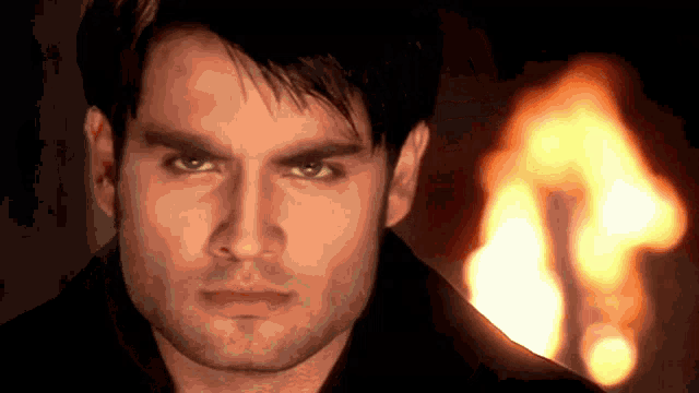 a close up of a man 's face with a flame in the background