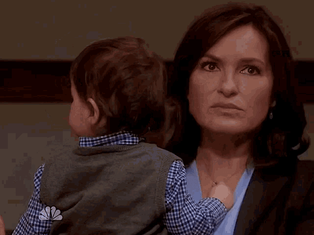 a woman is holding a small child with a nbc logo on her shirt
