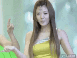 a woman in a yellow top is making a funny face with her hands
