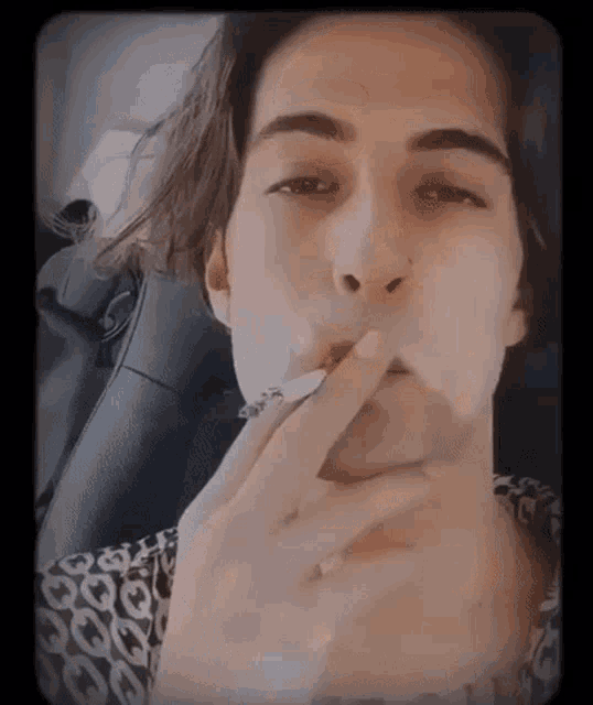 a young man is smoking a cigarette with his finger in his mouth
