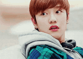 a young man wearing a plaid shirt and headphones looks at the camera