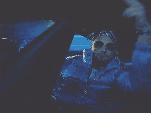 a man wearing sunglasses is sitting in a car with the word the maw on the window