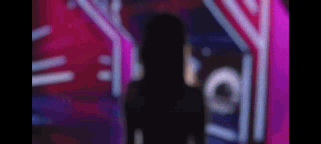 a silhouette of a woman is standing in front of a neon sign at night .