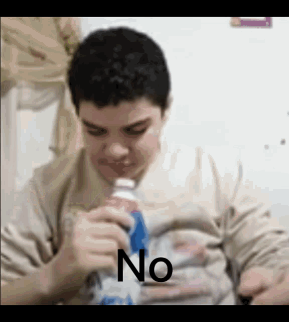 a young man is drinking from a bottle with the word no written on it