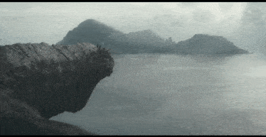a large rock sitting on top of a cliff overlooking a body of water .