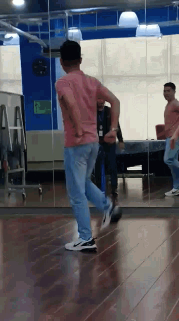 a man is dancing in front of a mirror in a gym