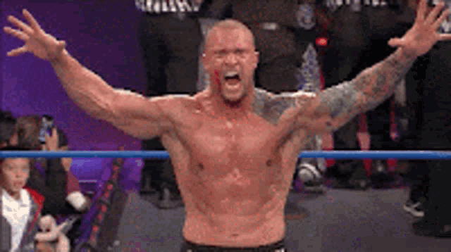 a shirtless wrestler with his arms outstretched in the air